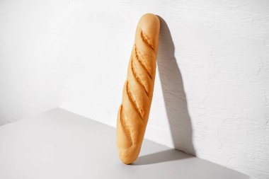Fresh baguette on table near white wall