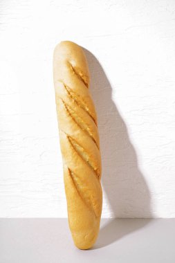 Fresh baguette on table near white wall