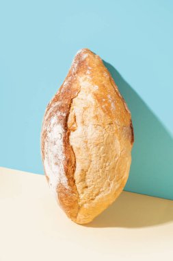 Loaf of fresh bread on beige table near blue wall
