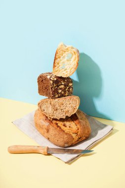 Loaves of different bread and knife on beige table near blue wall