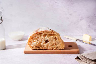 Board with half of fresh bread on white table