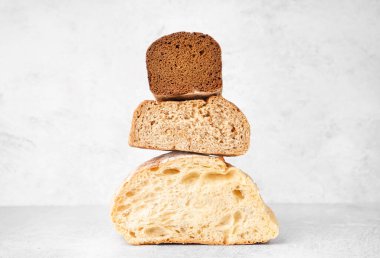 Stacked halves of different bread on white table