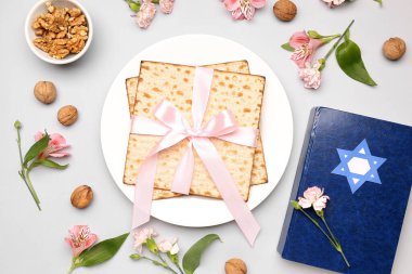 Composition with Jewish flatbread matza for Passover, Torah, walnuts and alstroemeria flowers on light background