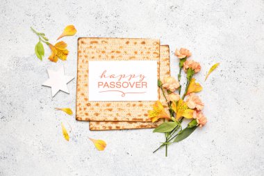 Composition with Jewish flatbread matza for Passover, greeting card and flowers on light background