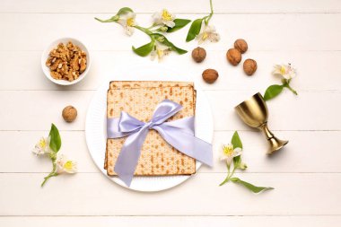 Composition with flatbread matza, walnuts and alstroemeria flowers on light wooden background