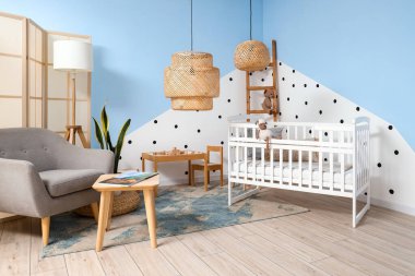 Interior of children's bedroom with crib, armchair and tables