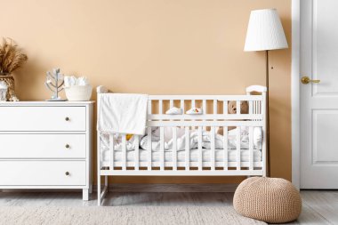 Interior of children's bedroom with crib, commode and lamp