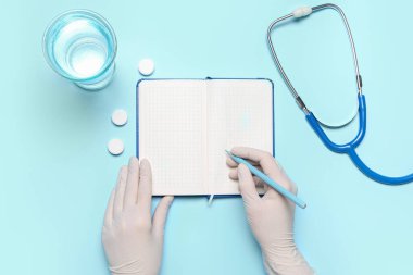Female doctor writing in notebook on blue background. World Health Day