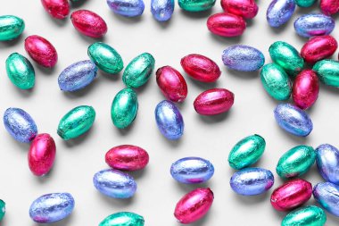 Chocolate Easter eggs in foil on light background