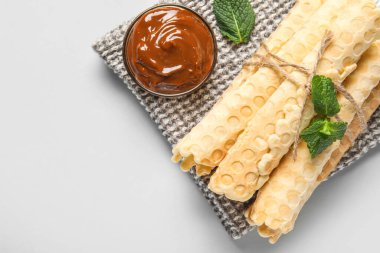 Napkin with delicious wafer rolls, boiled condensed milk and mint on grey background