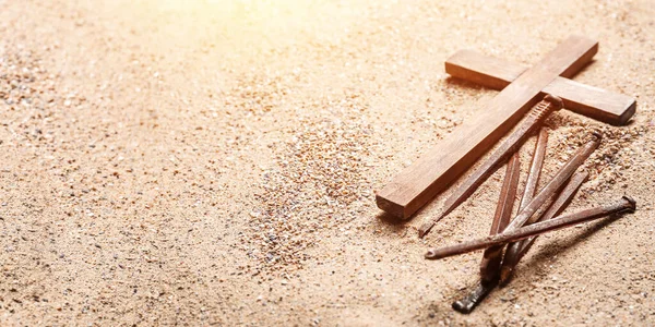 stock image Wooden cross and nails on sand, closeup. Good Friday concept