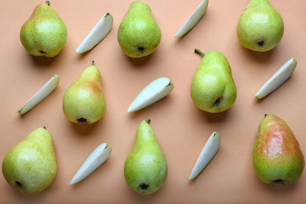 Composition with whole and cut pears on color background