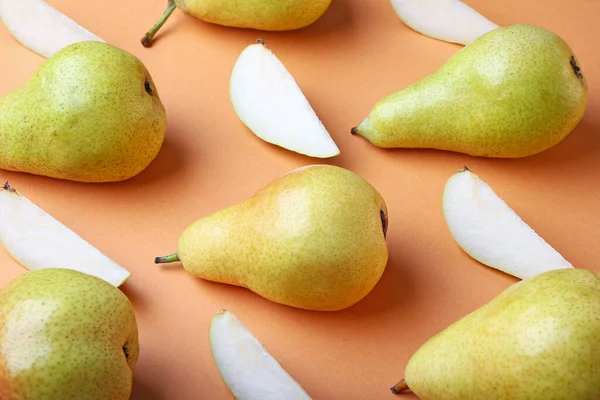 Composition with whole and cut pears on color background