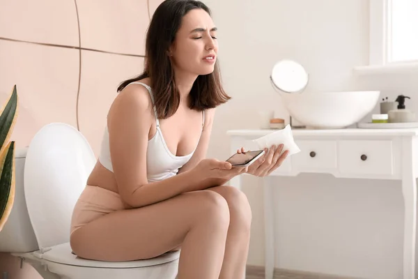 Mujer Joven Con Teléfono Móvil Almohadilla Menstrual Sentado Inodoro Baño — Foto de Stock