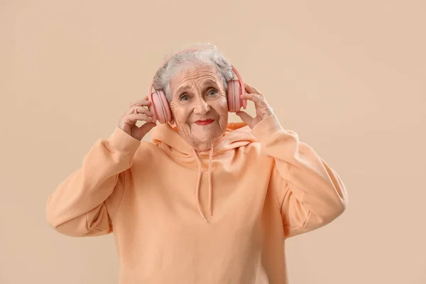 Starsza Kobieta Słuchawkach Beżowym Tle — Zdjęcie stockowe