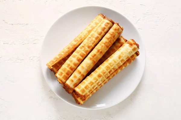 Plate of wafer rolls with boiled condensed milk on white grunge background