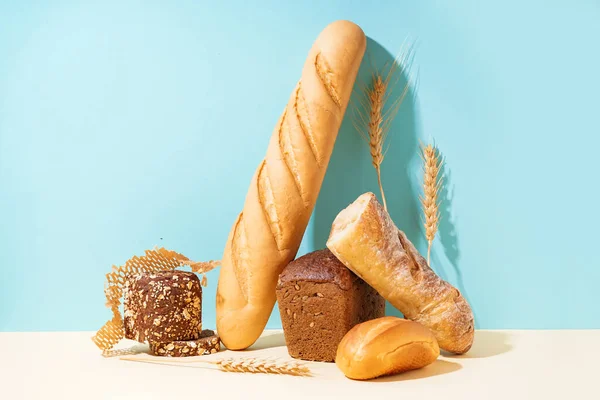 Mavi Duvarın Yanındaki Bej Masada Farklı Ekmek Buğday Kulakları — Stok fotoğraf