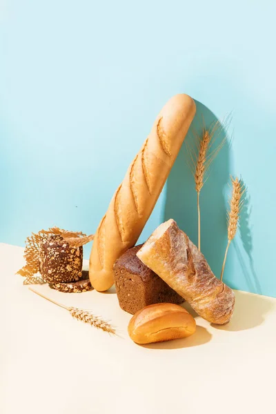 Mavi Duvarın Yanındaki Bej Masada Farklı Ekmek Buğday Kulakları — Stok fotoğraf