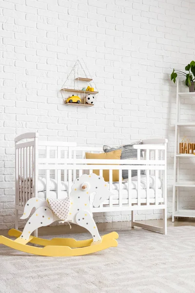 Interior of children\'s bedroom with crib and rocking horse