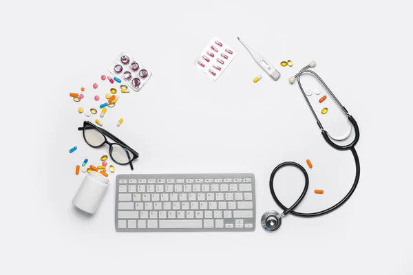 Frame made of pills, computer keyboard, thermometer and stethoscope on white background. World Health Day