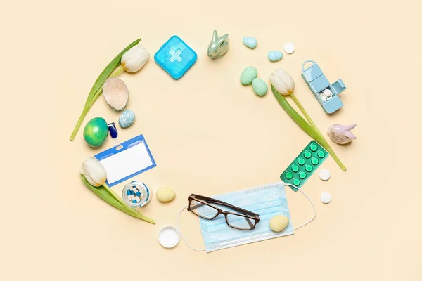 Frame made of pills, blank badge, tulips and Easter eggs on beige background. World Health Day