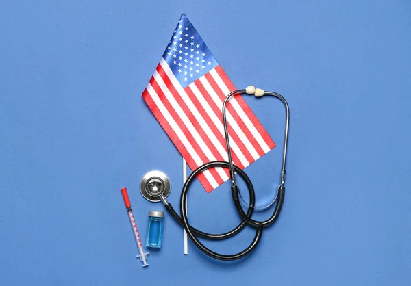 Stethoscope with vaccine, syringe and USA flag on blue background