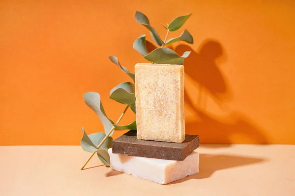 stock image Stack of natural soap bars and eucalyptus branch on color background