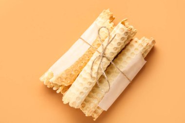 Stack of delicious wafer rolls tied with thread on orange background