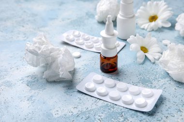 Nasal drops with pills, flowers and tissues on grunge background, closeup. Seasonal allergy concept