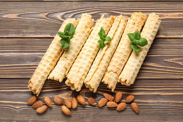 Delicious wafer rolls with almond nuts and mint on brown wooden background