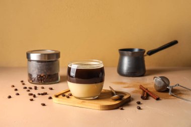 Wooden board with glass of tasty Cafe Bombon on color background