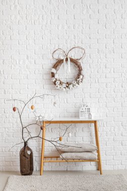 Interior of room with Easter wreath, table and tree branches