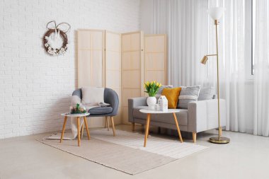 Interior of living room with Easter wreath, armchair and sofa
