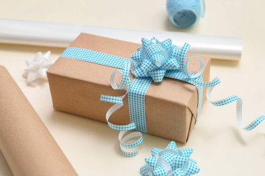 Gift box with bows and wrapping paper on light background, closeup