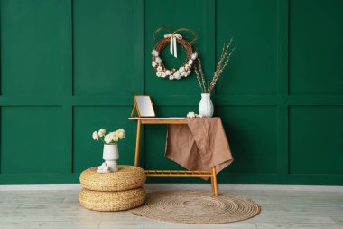 Interior of stylish room with Easter wreath, table and poufs