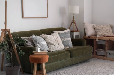 Interior of living room with cozy cushions on green sofa