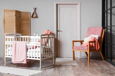 Interior of light children's bedroom with baby crib and armchair