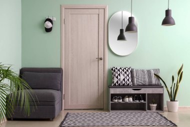 Interior of stylish hall with armchair and shoe stand
