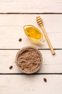 Jar of body scrub and honey on light wooden background