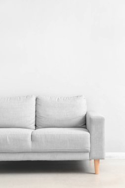 Stylish grey sofa near white wall