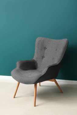 Modern grey armchair near green wall