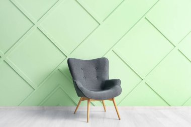 Yeşil duvarın yanındaki modern gri koltuk