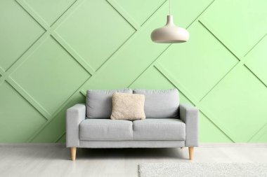 Stylish grey sofa near green wall