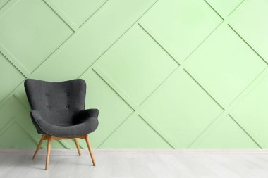 Modern grey armchair near green wall
