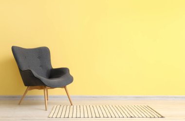 Modern grey armchair near yellow wall