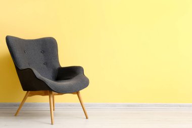 Sarı duvarın yanındaki modern gri koltuk