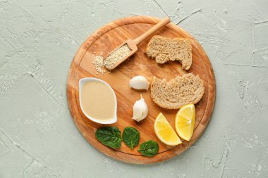 Tahinili ahşap tahta tahini, susam tohumu, ekmek, sarımsak ve limon dilimleri.