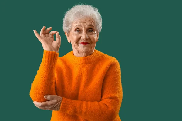 Старша Жінка Помаранчевому Светрі Показує Добре Зеленому Тлі — стокове фото
