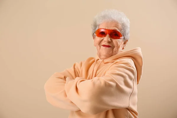 Старшая Женщина Солнечных Очках Толстовке Бежевом Фоне — стоковое фото