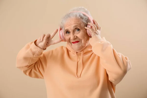 Senior Kvinna Hörlurar Visar Seger Gest Beige Bakgrund — Stockfoto